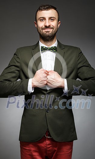 happy young man in a green suit on a gray background