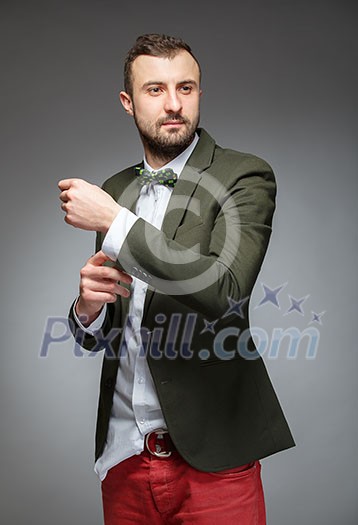 Portrait of handsome stylish man in elegant green suit. Grey background.