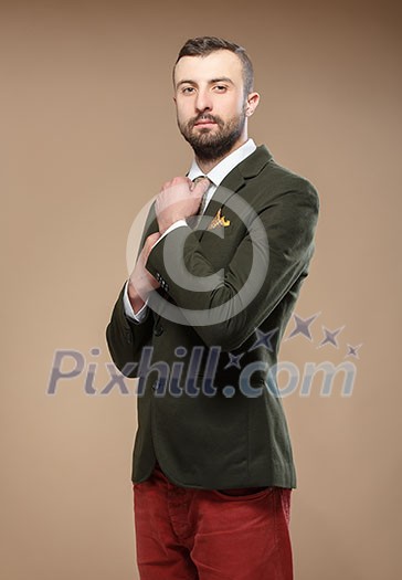 young man in a green suit and tie, beige background