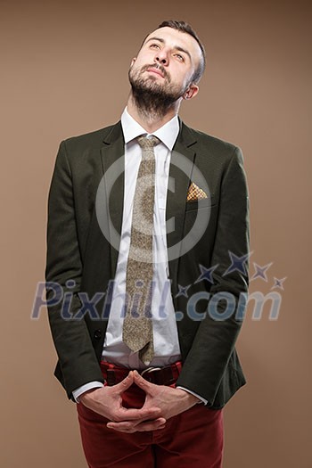 Dreaming Young stylish man in a green suit and orange jeans. Beige background Dreaming Young stylish man in a green suit and orange jeans. Beige background