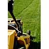 Yellow lawn mower on the green grass. Caring for a garden. Shallow depth of field. Focus on grass.