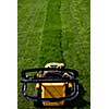 Yellow lawn mower on the green grass. Caring for a garden. Shallow depth of field.