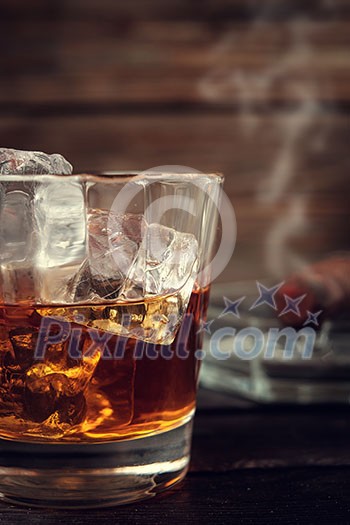 Whiskey and cigar on wooden background close up. Vitage toned.