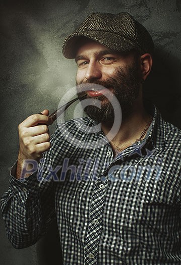 Portrait of young stylish man with a beard with a pipe.
