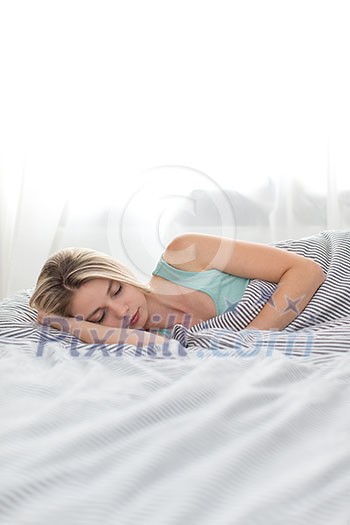 Beautiful young woman sleeping in bed (color toned image; shallow DOF)