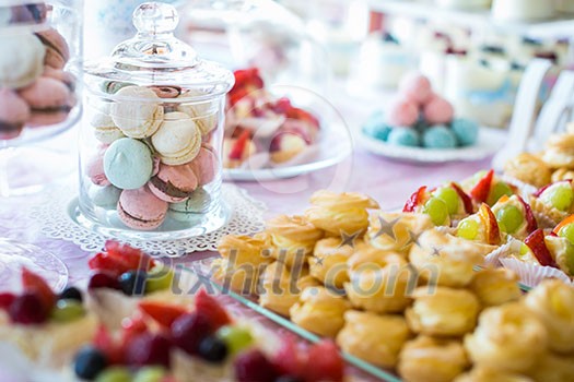 Table setting. Colorful macarons and cakes.
