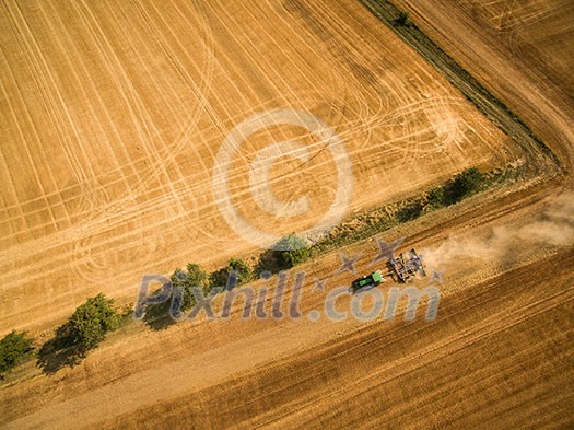 Aerial view of a tractor working a field after harvest Aerial view of a tractor working a field after harvest