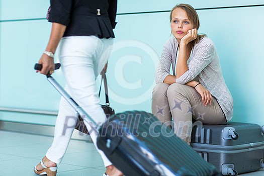 Young, female frustrated passenger at the airport, waiting desperately for her delayed flight (color toned image; shallow DOF)