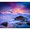 Tropical beach vacation background - waves and rocks on beach on sunset with beautiful cloudscape
