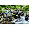 Woman doing yoga asana Natarajasana - Lord of the dance pose outdoors at waterfall in Himalayas