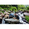 Woman doing Ashtanga Vinyasa yoga asana Utthita trikonasana - extended triangle pose outdoors at waterfall in Himalayas