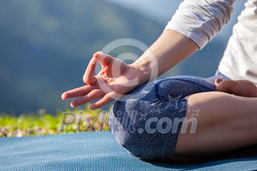 Close up of woman in Padmasana yoga lotus pose with chin mudra outdoors with copyspace