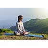 Sporty fit woman practices yoga asana Baddha Konasana - bound angle pose outdoors in Himalayas mountains in the morning. Himachal Pradesh, India