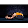 Sporty fit woman practices Ashtanga Vinyasa yoga back bending asana Paschimottanasana - seated forward bend