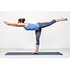 Beautiful sporty fit woman practices yoga asana Virabhadrasana 3 - warrior 3 pose