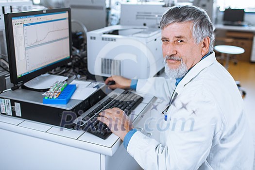 Senior researche rusing a computer in the lab while working on an experiment (color toned image)