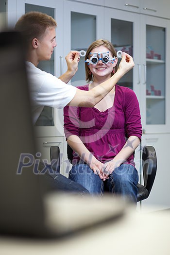 optometry concept - pretty young woman having her eyes examined by an eye doctor