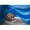 Detail of a hand of a patient being monitored dusing surgery - vital functions of the body are being closely watched by the anaesthesiologist (color toned image, shallow DOF)