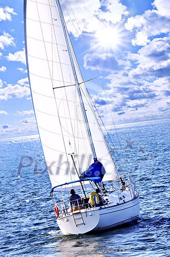 Sailboat with white sail sailing on a sunny day