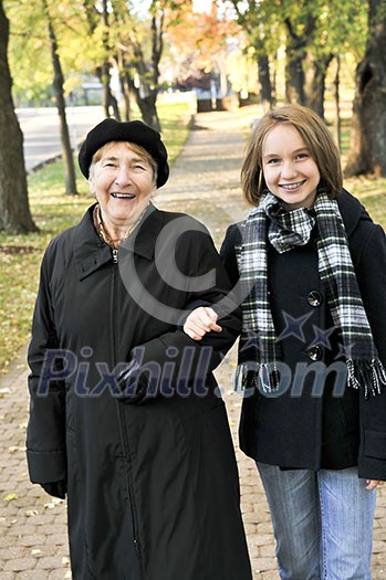 Teen granddaughter walking with grandmother in autumn park Teen granddaughter walking with grandmother in autumn park
