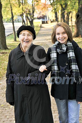 Teen granddaughter walking with grandmother in autumn park