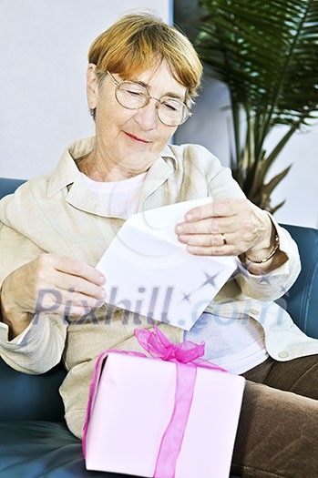 Elderly woman opening birthday card and present