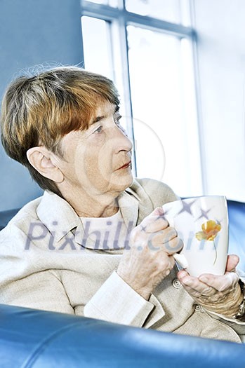 Sad elderly woman sitting with cup of tea Sad elderly woman sitting with cup of tea