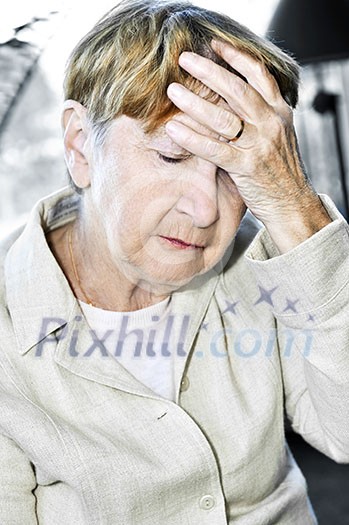 Sad senior woman holding her hand over forehead