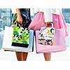 Two young girl friends holding shopping bags at mall