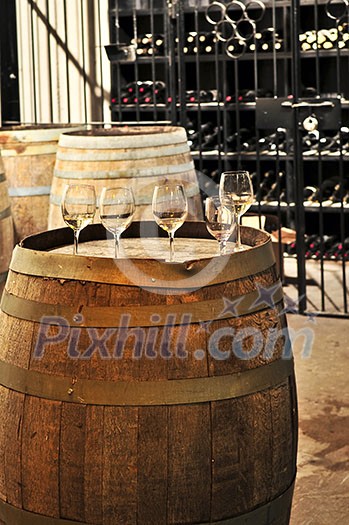 Row of wine glasses on barrel in winery cellar