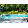 Backyard with outdoor inground residential swimming pool, garden, deck and stone patio