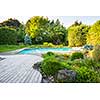 Backyard rock garden with outdoor inground residential swimming pool, curved wooden deck and stone patio