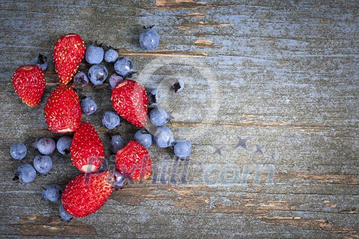 Wild strawberries and blueberries on old blue wooden background with copy space
