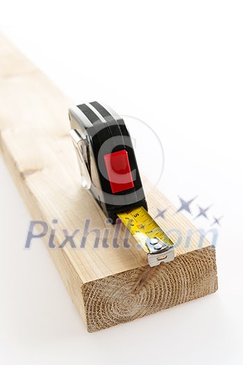 Metal imperial metric tape measure measuring two by four lumber on white background Metal imperial metric tape measure measuring two by four lumber on white background