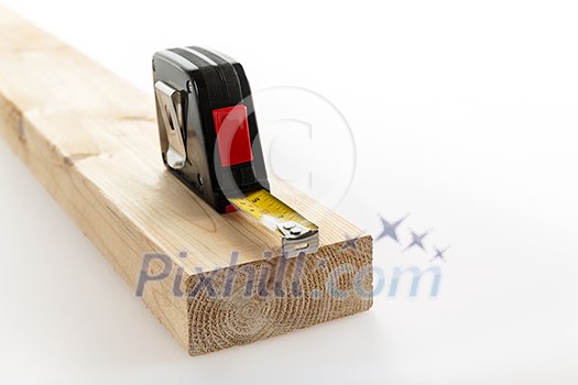 Metal imperial metric tape measure measuring two by four lumber on white background Metal imperial metric tape measure measuring two by four lumber on white background