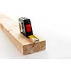 Metal imperial metric tape measure measuring two by four lumber on white background