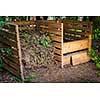 Wooden compost boxes with composted soil and yard waste for garden composting in backyard