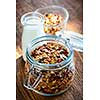 Homemade granola in open glass jar and milk or yogurt  on rustic wooden background
