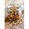 Homemade granola in open glass jar on rustic wooden background