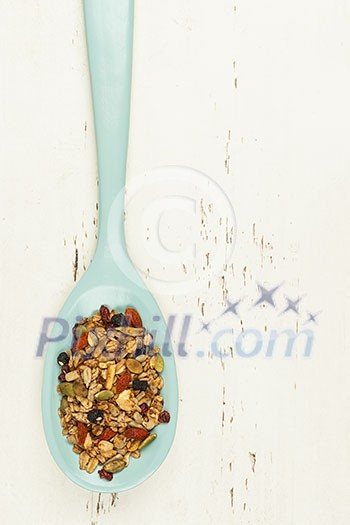 Homemade granola with various seeds and berries in wooden spoon shot from above