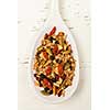 Homemade granola with various seeds and berries in white wooden spoon shot from above