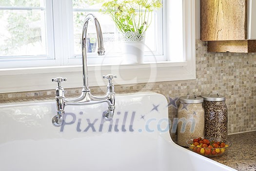 Rustic white porcelain kitchen sink with curved faucet and tile backsplash under large window