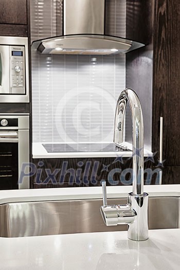 Elegant faucet and sink in island counter of modern kitchen Elegant faucet and sink in island counter of modern kitchen