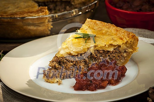 Slice of traditional pork meat pie Tourtiere with apple and cranberry chutney from Quebec, Canada.