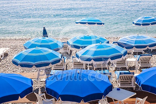 Blue umbrellas and chairs on pebble beach in Nice, France. Blue umbrellas and chairs on pebble beach in Nice, France.