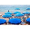 Blue umbrellas and chairs on pebble beach in Nice, France.