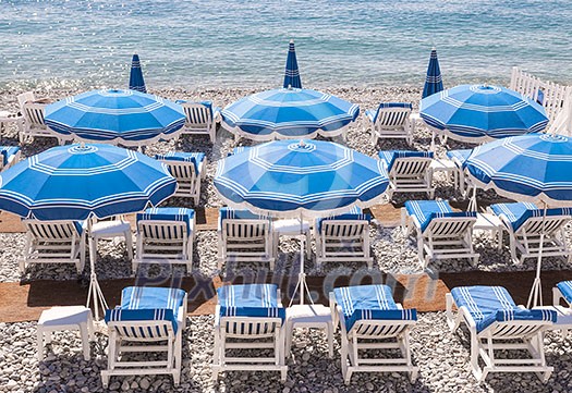 Blue umbrellas and chairs on pebble beach in Nice, France. Blue umbrellas and chairs on pebble beach in Nice, France.
