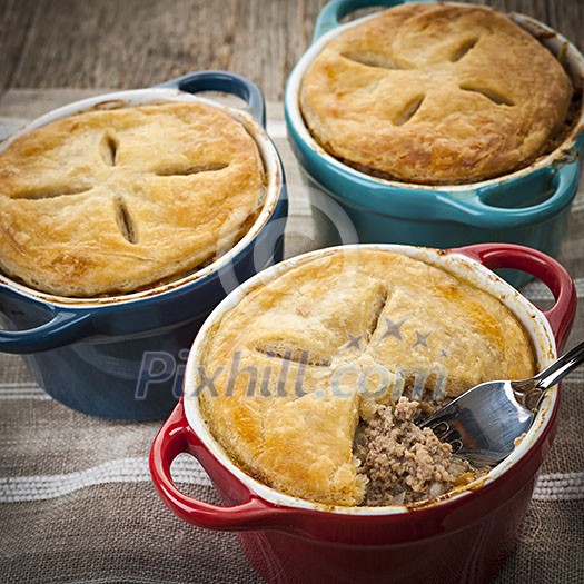 Closeup of three homemade gourmet meat pies with fork showing ground beef filling Closeup of three homemade gourmet meat pies with fork showing ground beef filling