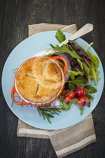 Gourmet meat pie with garden salad served on plate from above