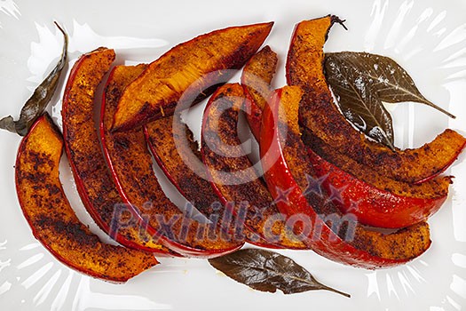 Roasted pumpkin slices served on white plate from above close up Roasted pumpkin slices served on white plate from above close up